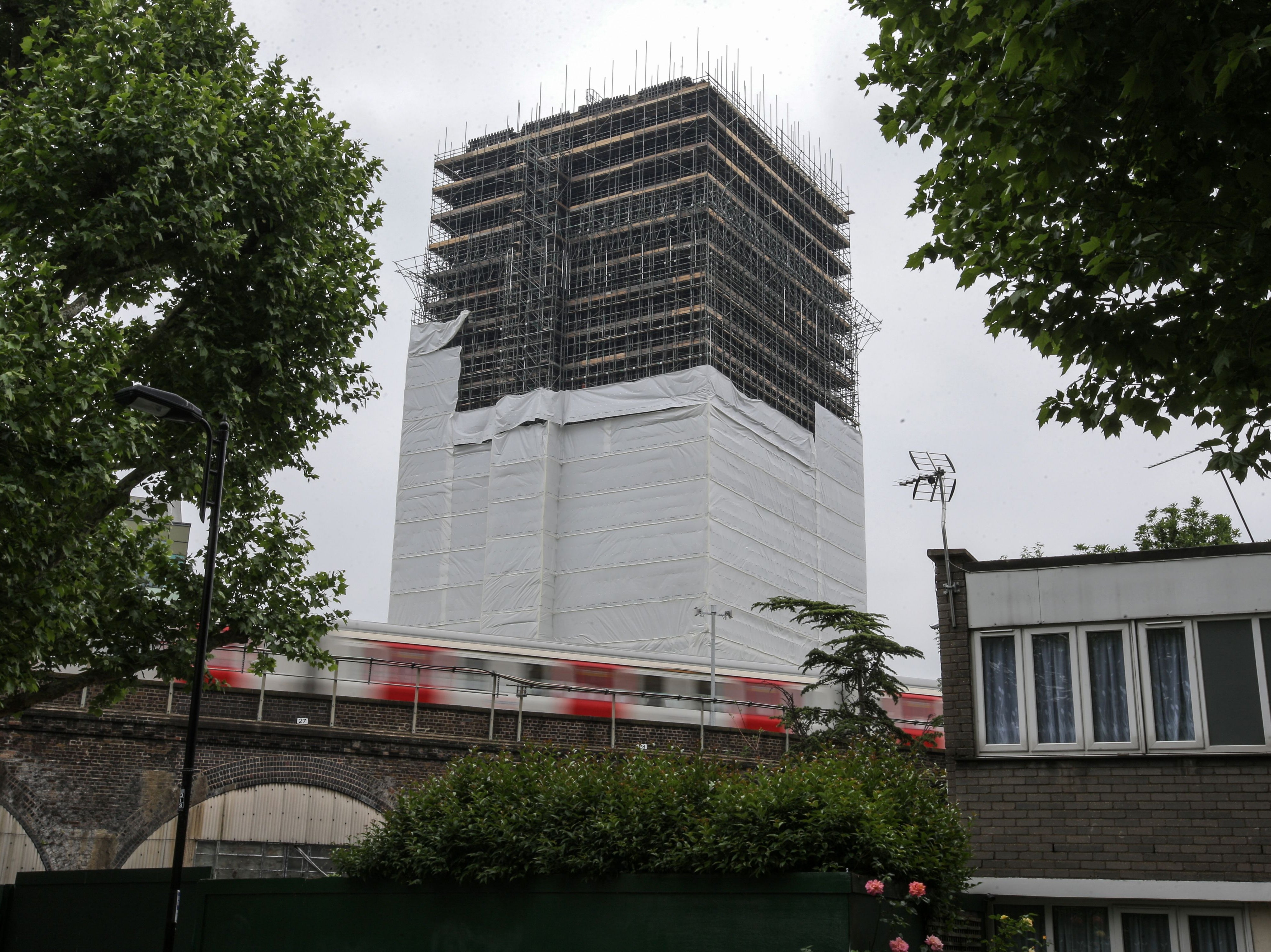 A tube train passes the burned-out shell of Grenfell Tower block in west London on May 25, 2018.