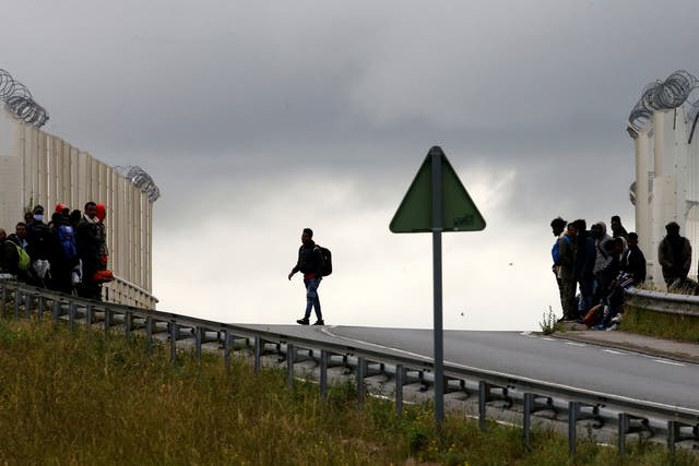 Migrants leave as French police officers dismantle a makeshift shelter camp in Calais