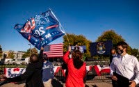 A Biden supporter attempts to grab Genevieve Peters, a member of Women for Trump, Trump flag near the front of the stage as Sen. Bernie Sanders speaks at a car rally campaign event for Democratic presidential candidate former Vice President Joe Biden on Monday, Oct. 5, 2020, in Warren, Mich. (Nicole Hester/Ann Arbor News via AP)