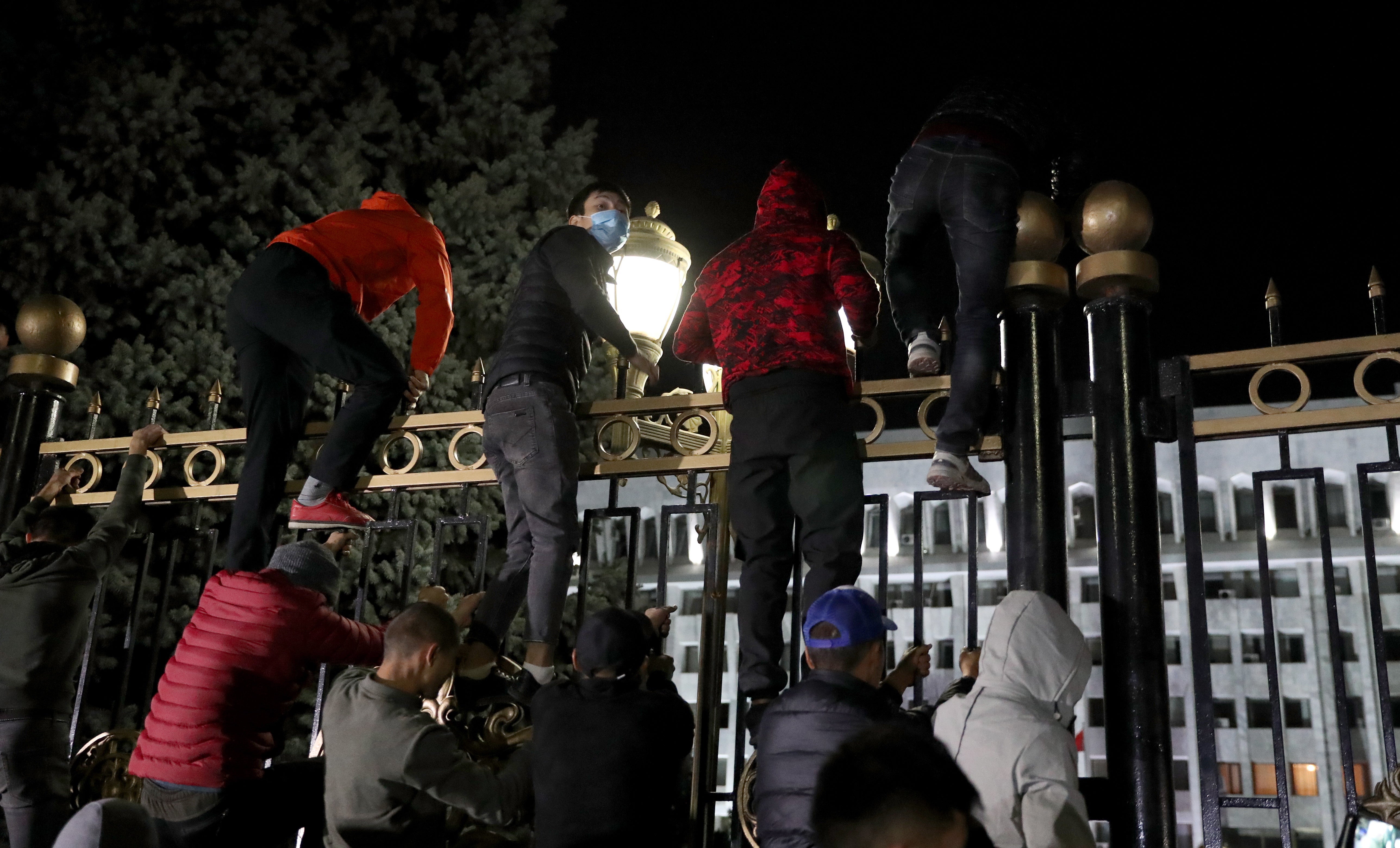 Opposition protesters storm the gates of the parliamentary building, known as the 'White House', in Bishkek