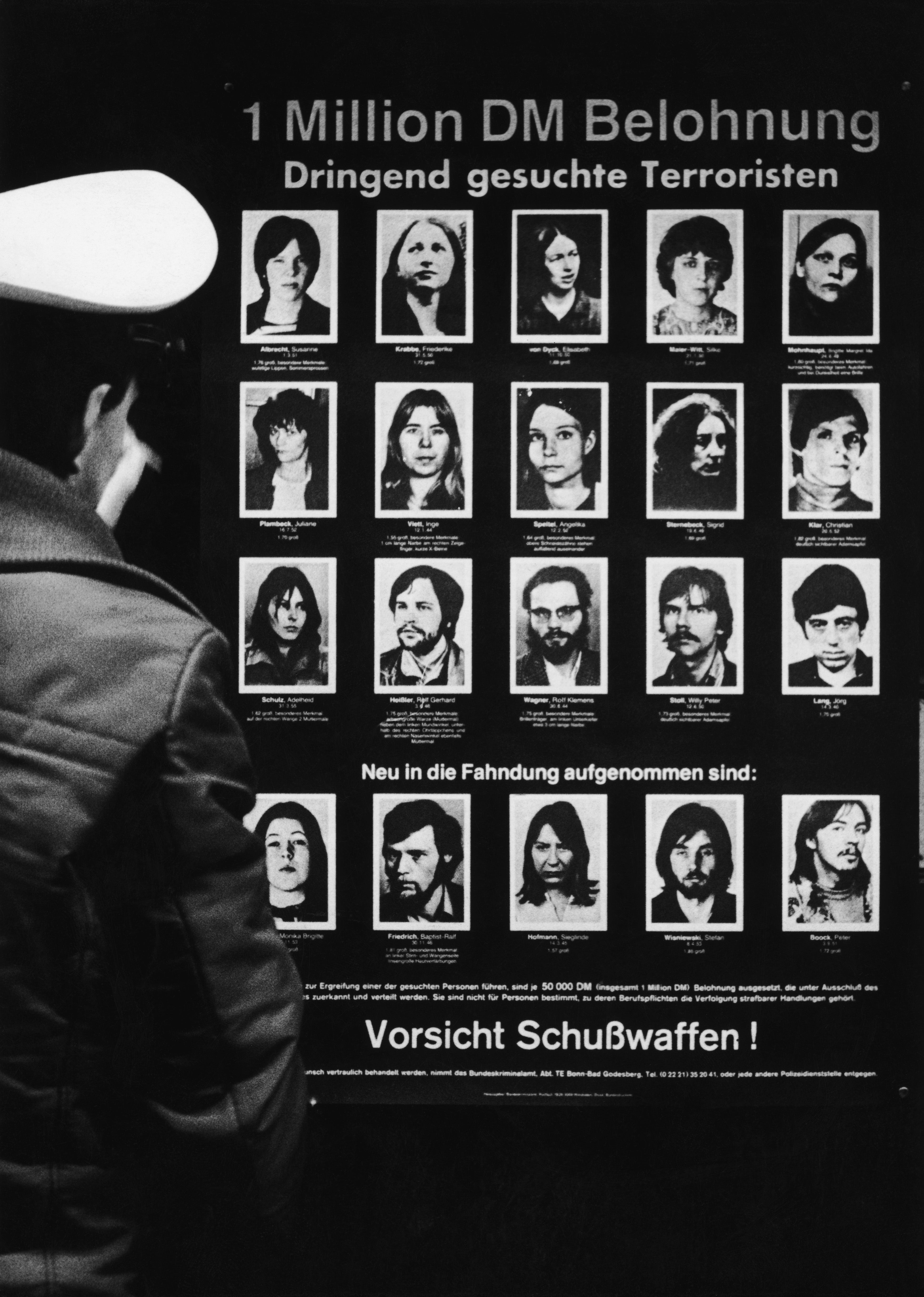 A West-German policeman reading a wanted poster offering a one-million-mark reward for information leading to the capture of 20 members of the Baader-Meinhof gang circa 1980