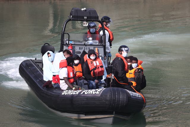 Border Force officers bring migrants from a small boat to shore at Dover