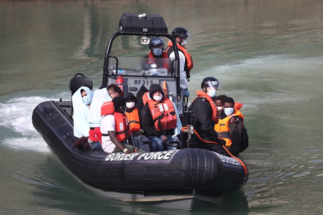 Border Force officers bring migrants from a small boat to shore at Dover