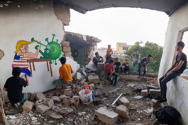 Syrian artists paints a mural in Idlib of Trump fighting coronavirus