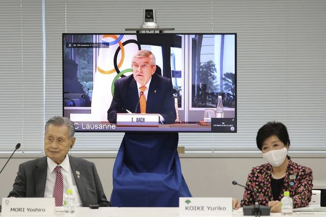 En esta imagen de archivo del 24 de septiembre de 2020, el presidente del COI, Thomas Bach, aparece en la pantalla para intervenir a distancia con el presidente del Comité Organizador Yoshiro Mori, a la izquierda, y la gobernadora de Tokio, Yuriko Koike, a la derecha durante una reunión virtual sobre los aplazados Juegos Olímpicos de Tokio, en Tokio. (Du Xiaoyi/Pool Foto via AP)