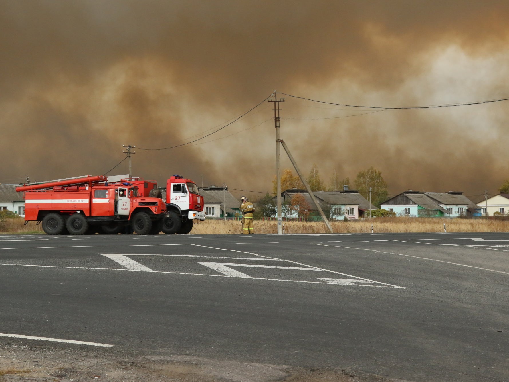Smoke rises from a fire at a munitions depot as fire engines are seen on a road in the Ryazan region