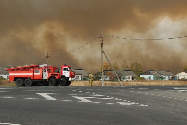 Smoke rises from a fire at a munitions depot as fire engines are seen on a road in the Ryazan region
