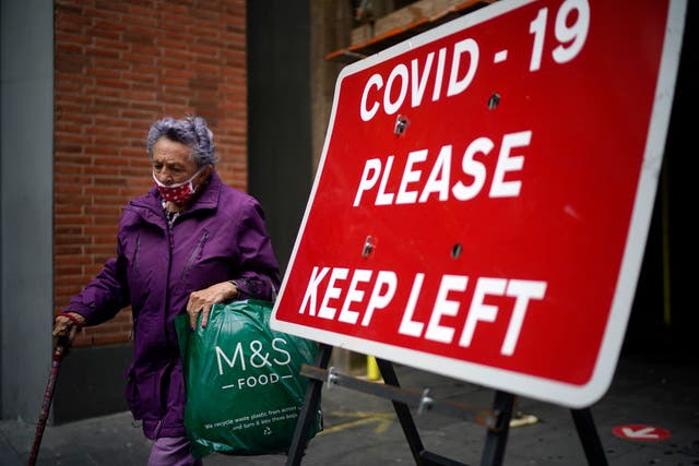 A woman passes a social distancing sign in Liverpool