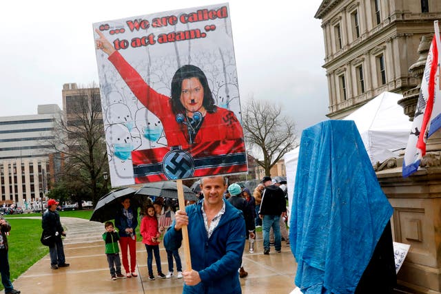 A protestor with a sign that has Michigan Gov. Gretchen Whittmer depicted as Adolph Hitler is seen at an American Patriot Rally organized by Michigan United for Liberty protest for the reopening of businesses, on the steps of the Michigan State Capitol in Lansing, Michigan on April 30, 2020. - The group is upset with Michigan Gov. Gretchen Whitmer's mandatory closure to curtail Covid-19. (Photo by JEFF KOWALSKY / AFP) (Photo by JEFF KOWALSKY/AFP via Getty Images)