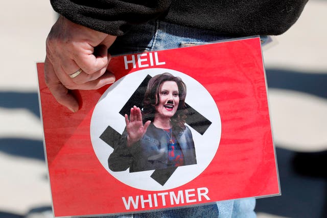 <p>A protester with a sign comparing Gretchen Whitmer’s to Hitler over lockdown orders</p>