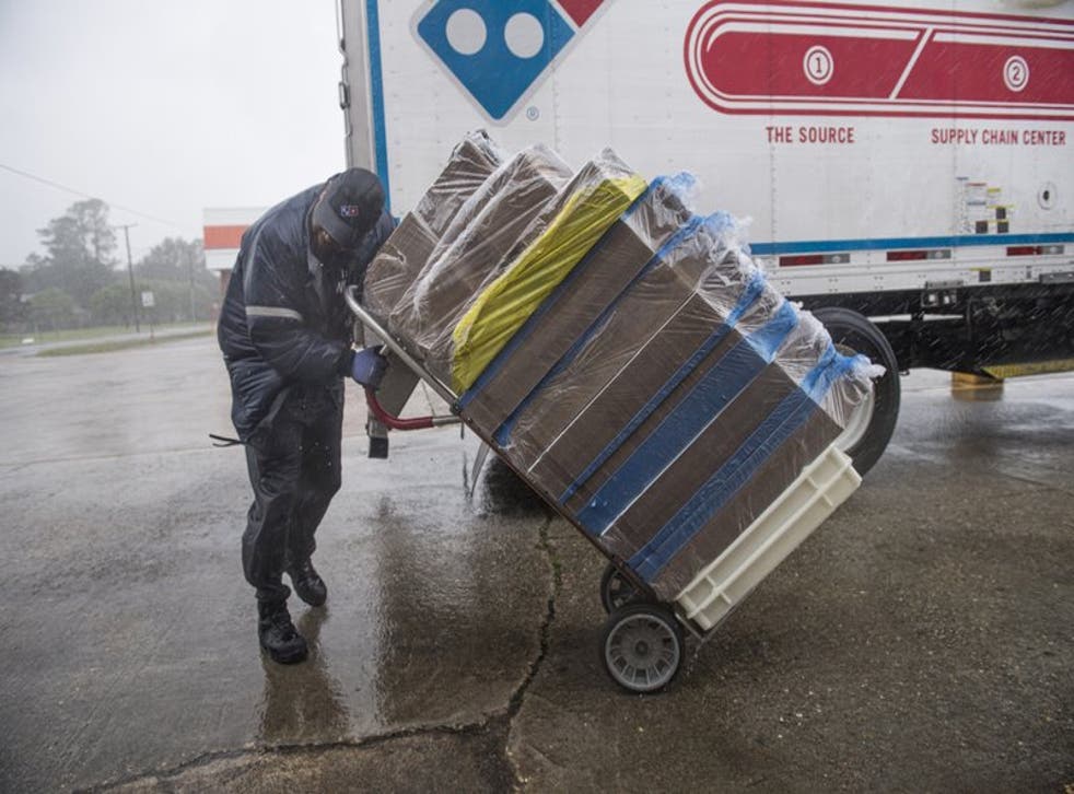 Tran Williams, chofer para Domino’s Pizza, pasa trabajos para empujar su carretilla ante la fuerza de los vientos del huracán Delta en Jennings, Luisiana, el viernes, 9 de octubre del 2020. Delta llegó el viernes como una tormenta de Categoría 2 al suroeste del estado. (Chris Granger/The Advocate vía AP)