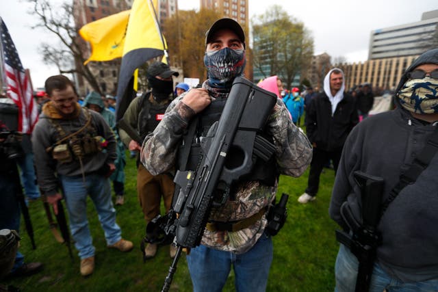 A protester carries his rifle at the State Capitol in Lansing, Michigan, in April