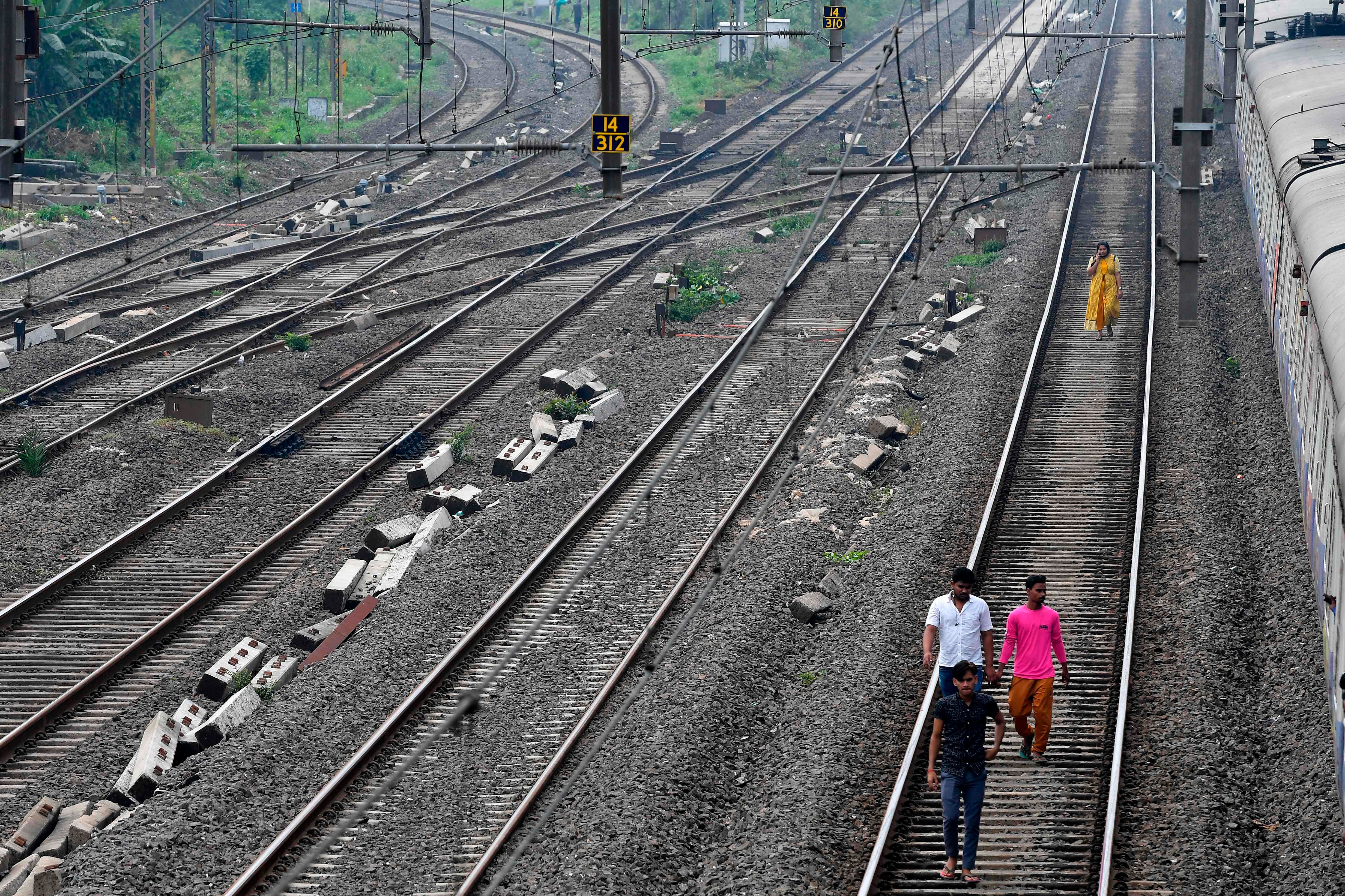 Passengers walk on a railway track after trains got stranded due to a major power cut in Mumbai