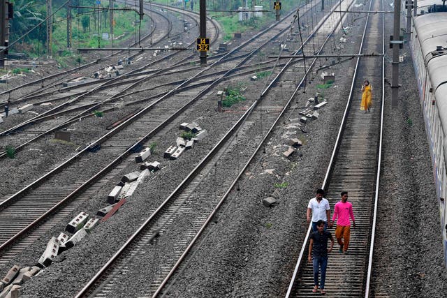 Passengers walk on a railway track after trains got stranded due to a major power cut in Mumbai