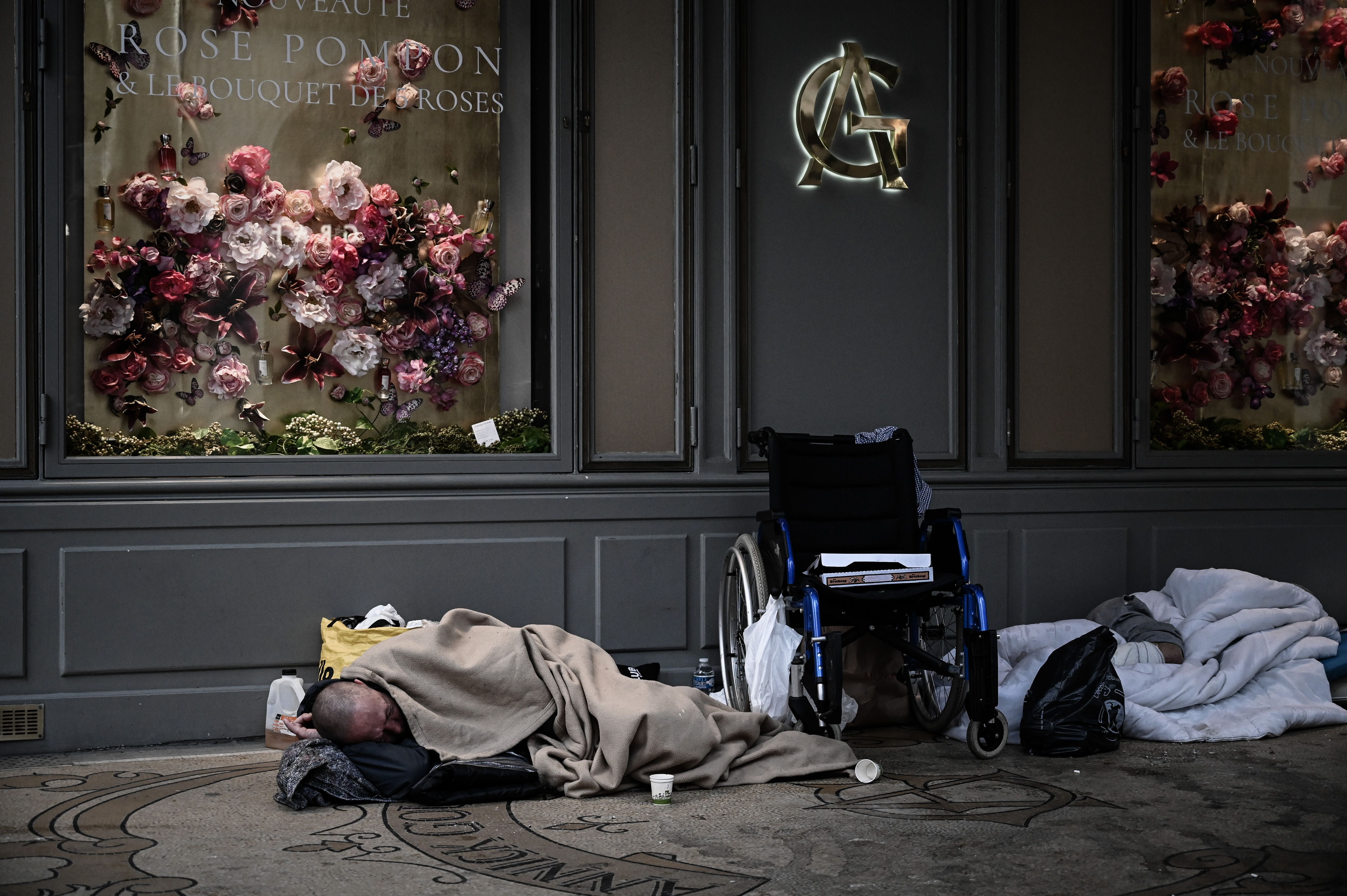 A homeless man sleeps in front of closed shops in Paris on 17 April 2020 during the first coronavirus lockdown