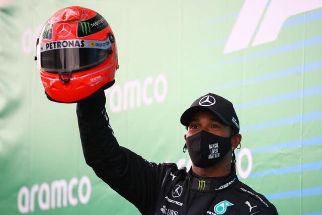 Lewis Hamilton celebrates winning the Eifel Grand Prix after being presented with Michael Schumacher’s helmet