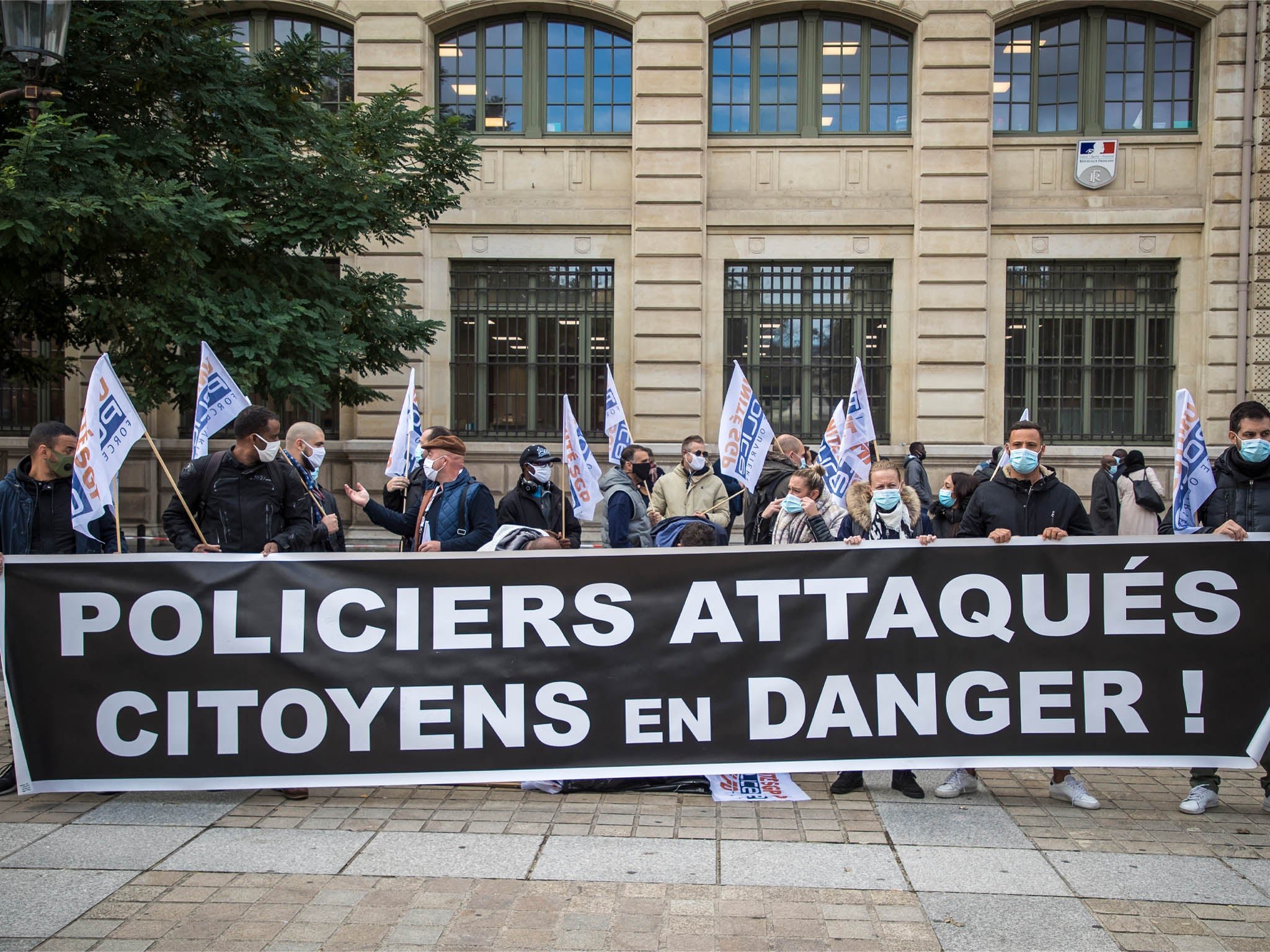 Members of French Police labor unions hold a banner reading “Policemen attacked, citizens in danger!” as they protest outside the Prefecture of Paris