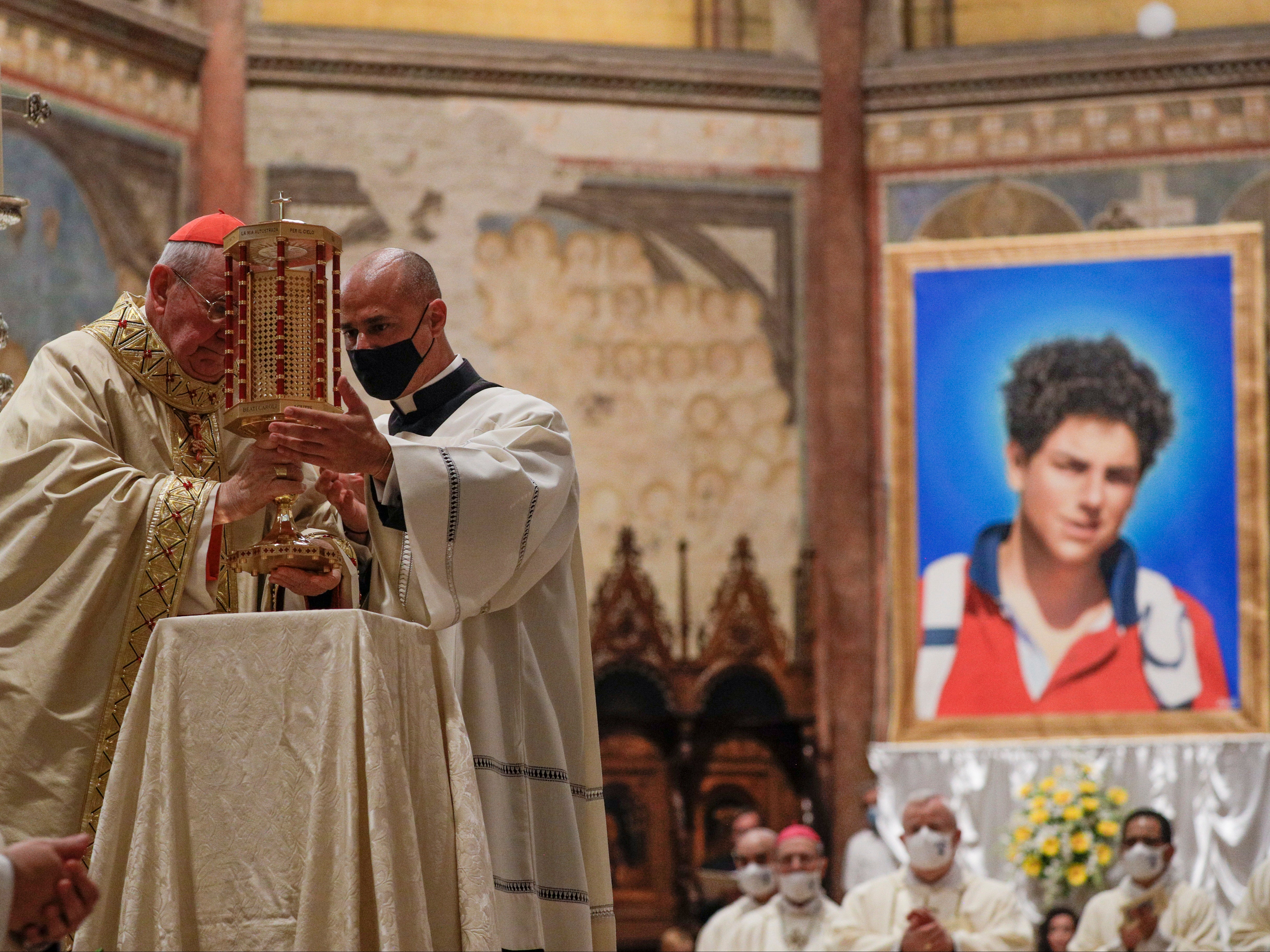 Cardinal Agostino Vallini (L) holds a relic of 15-year-old Carlo Acutis, who died in 2006 of leukaemia, during his beatification ceremony