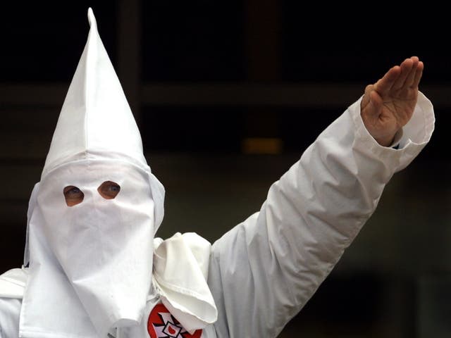 <p>A Klansman raises arm during a “white power” chant at a KKK rally in 2000</p>