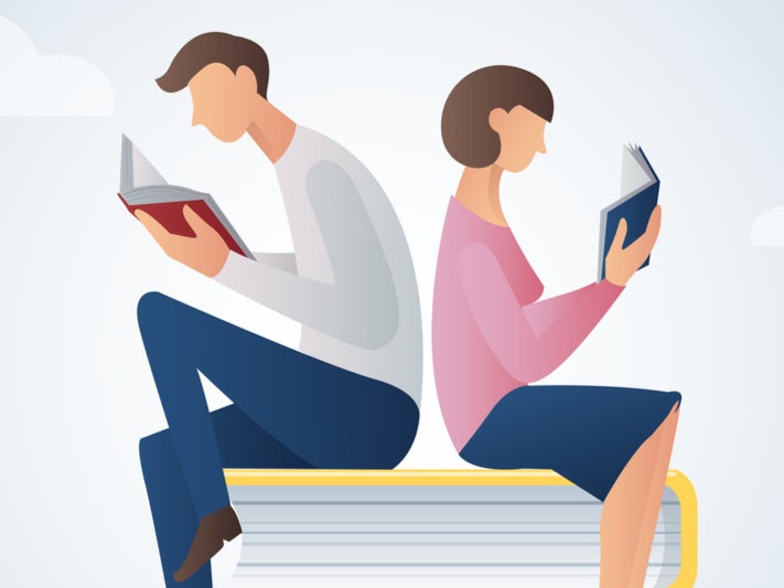 man and woman reading books sitting on many books