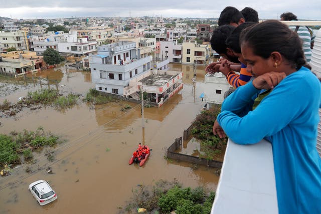 Residents look at a street inundated with floodwater after heavy rainfall in Hyderabad, India
