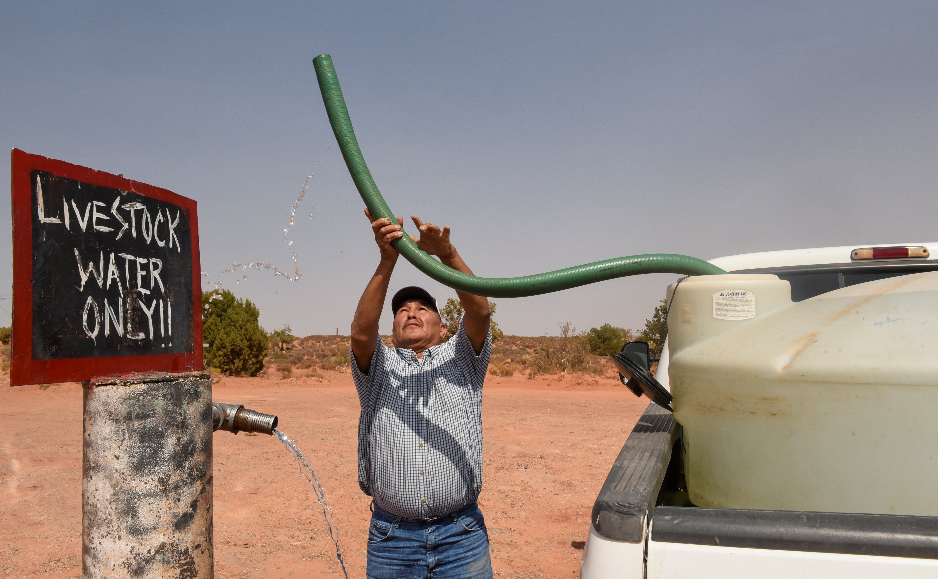 Eugene Boonie, 55, of the Navajo Nation fills up his water tank at a livestock spigot