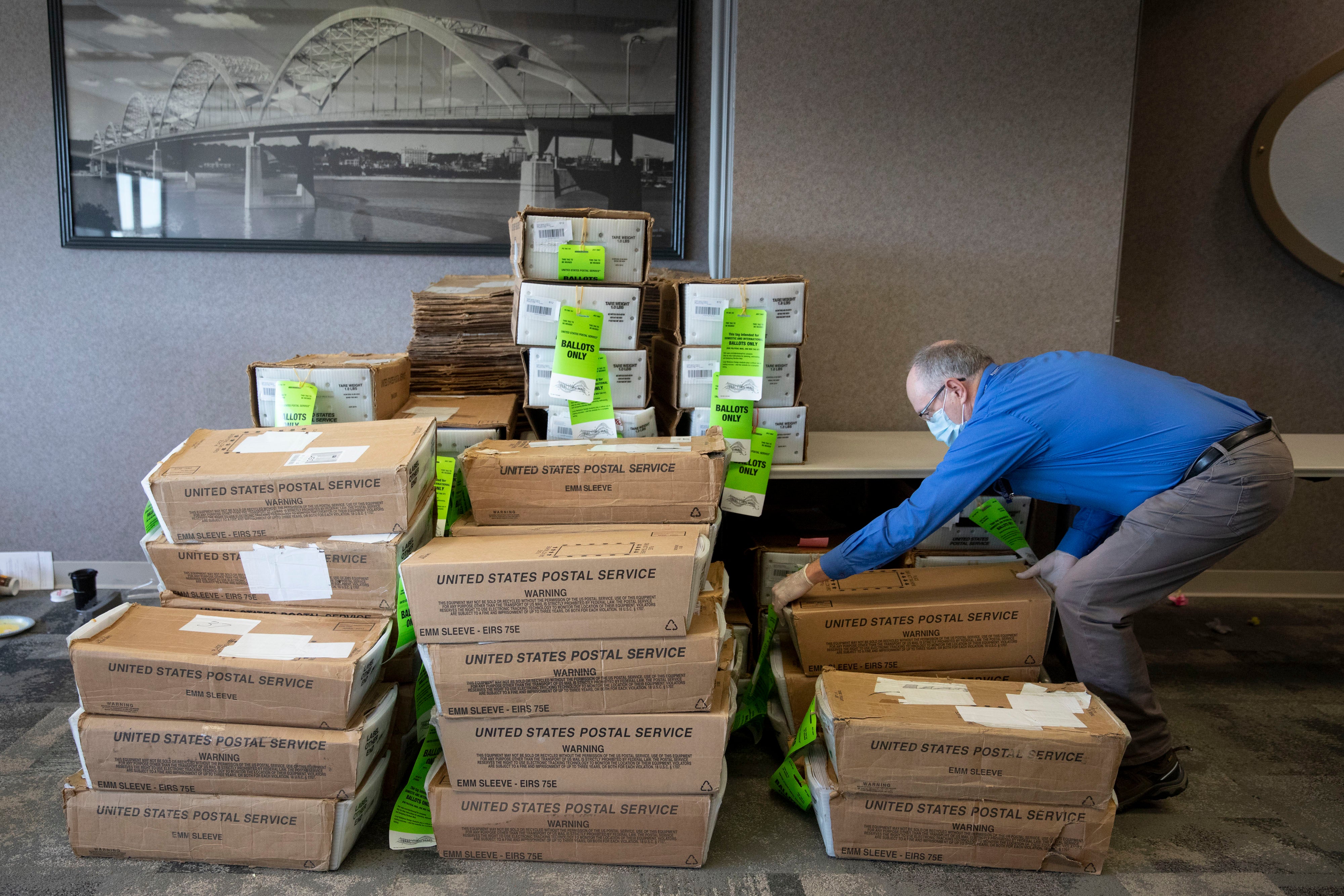 Auditors office employee Roland Caldwell picks up a box of absentee ballots at the Scott County, Iowa, auditor's office in Davenport on Monday