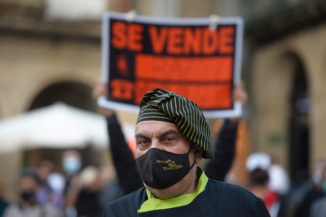 A cook stands next to a for sale sign during a protest in support of restaurants and bars  in Ourense, northwestern Spain, on October 14, 2020