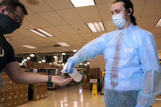 Ethan Johnson, derecha, rocía sanitizante en las manos de un cliente que ingresa a la tienda de cómputo Micro Center el 21 de septiembre de 2020, en Dallas, con el fin de ayudar a prevenir contagios de coronavirus. (AP Foto/LM Otero)