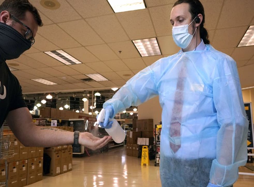 Ethan Johnson, derecha, rocía sanitizante en las manos de un cliente que ingresa a la tienda de cómputo Micro Center el 21 de septiembre de 2020, en Dallas, con el fin de ayudar a prevenir contagios de coronavirus. (AP Foto/LM Otero)