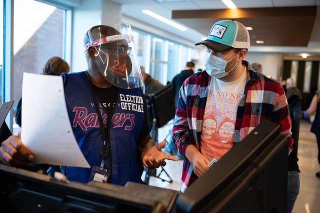 Brian Jones, 56, (L) ayuda al votante por primera vez Andrew Smith, de 25, en la votación durante la votación anticipada el 16 de octubre en la sede de la junta electoral en Painesville, Ohio.