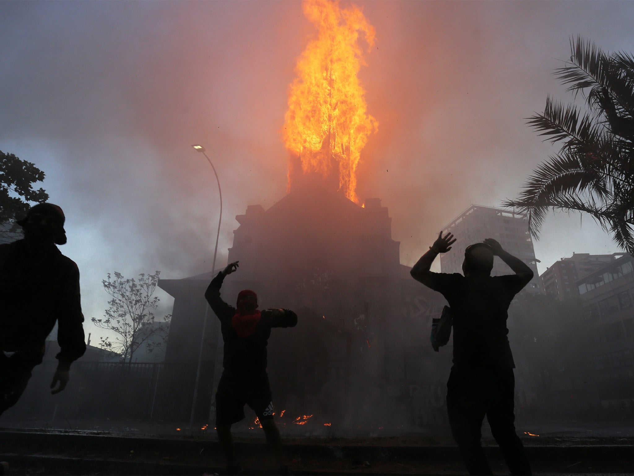 Firefighters working to extinguish fire in the aftermath of a protest in Santiago, 18 October 2020