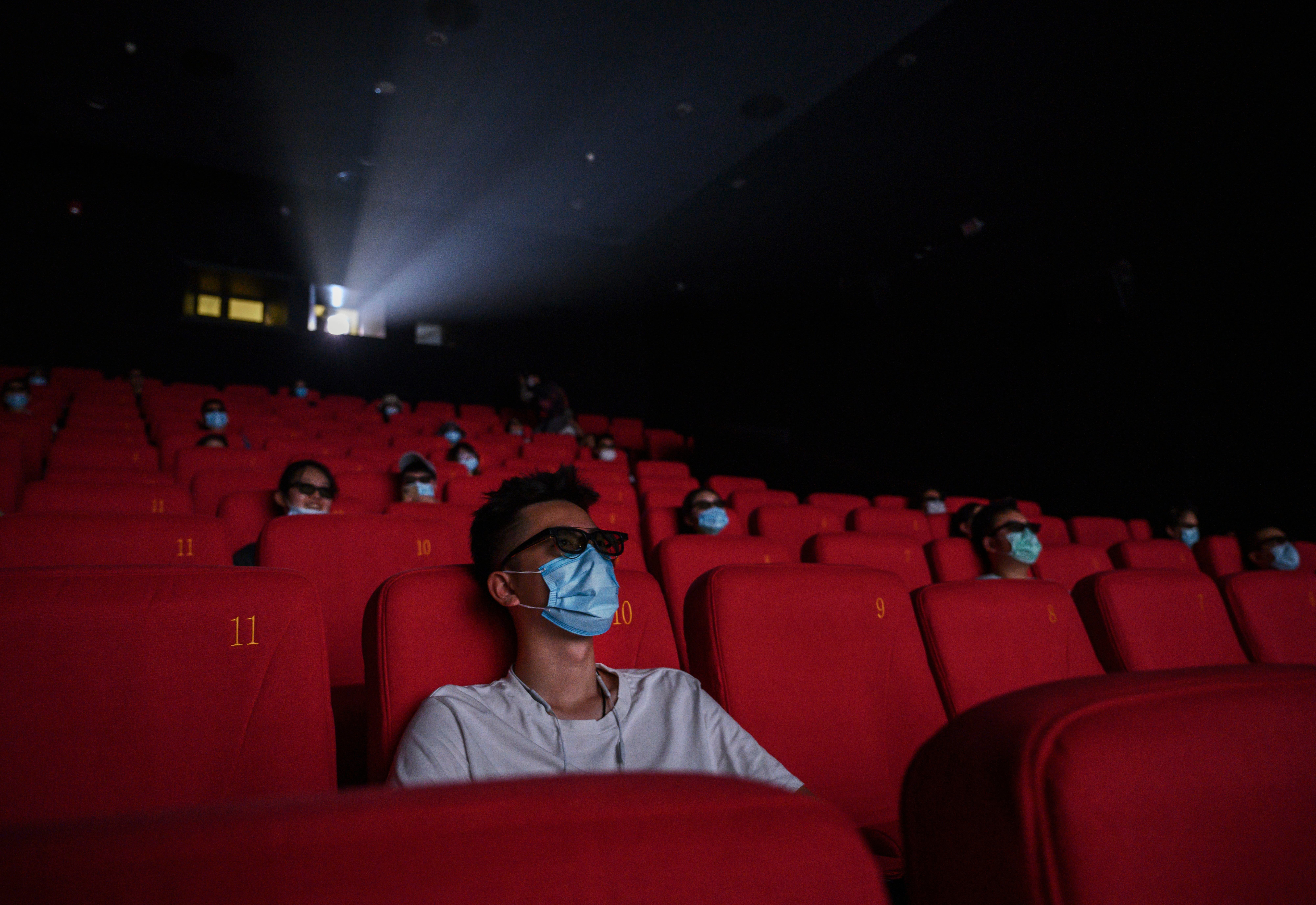 People wear protective masks as they watch a movie in 3D at a theatre in Beijing, China