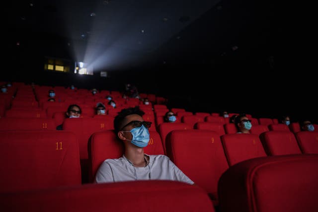 People wear protective masks as they watch a movie in 3D at a theatre in Beijing, China