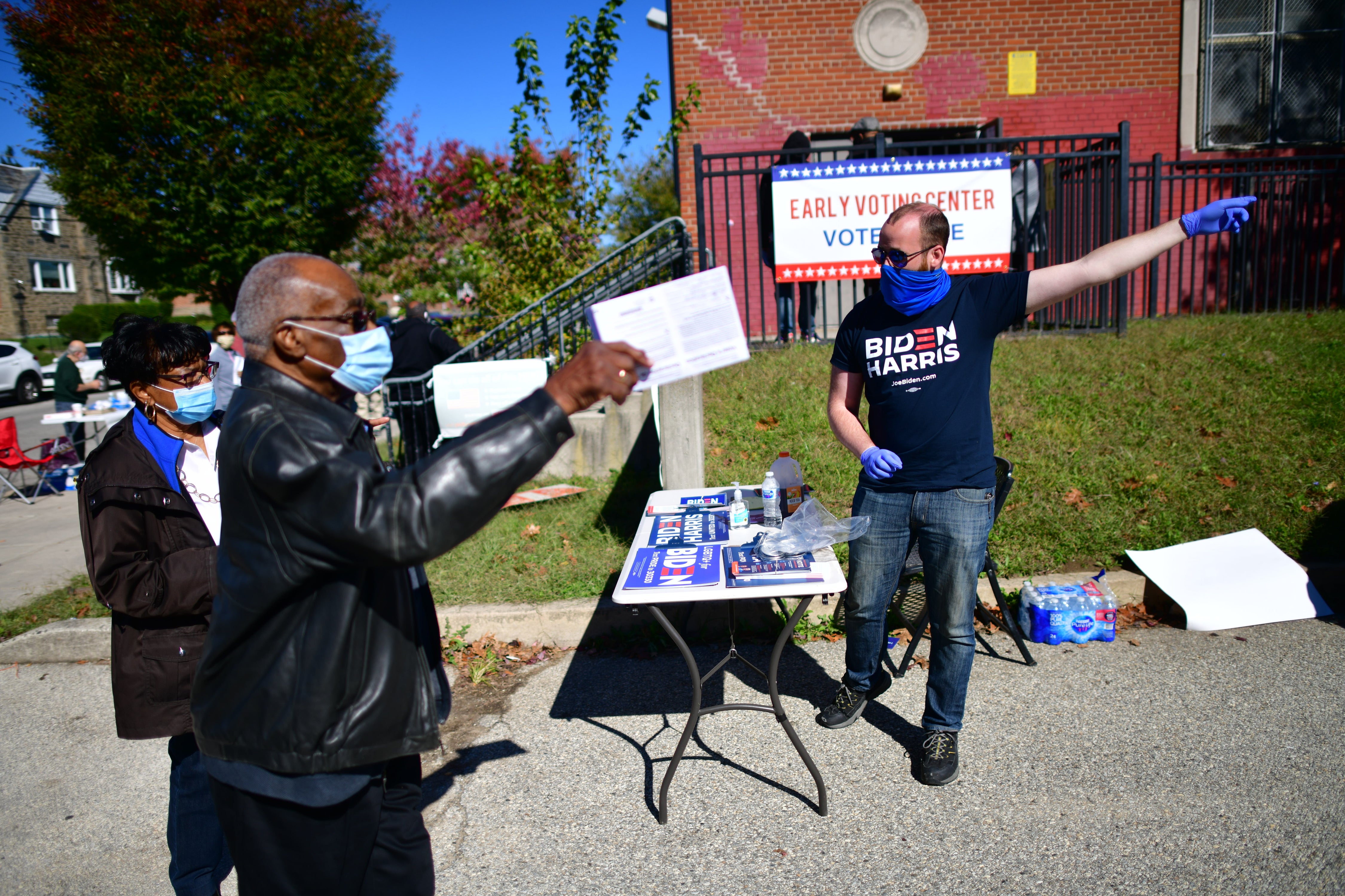 A Biden campaign volunteer directs early voters at the A B Day School poll in Philadelphia, Pennsylvania