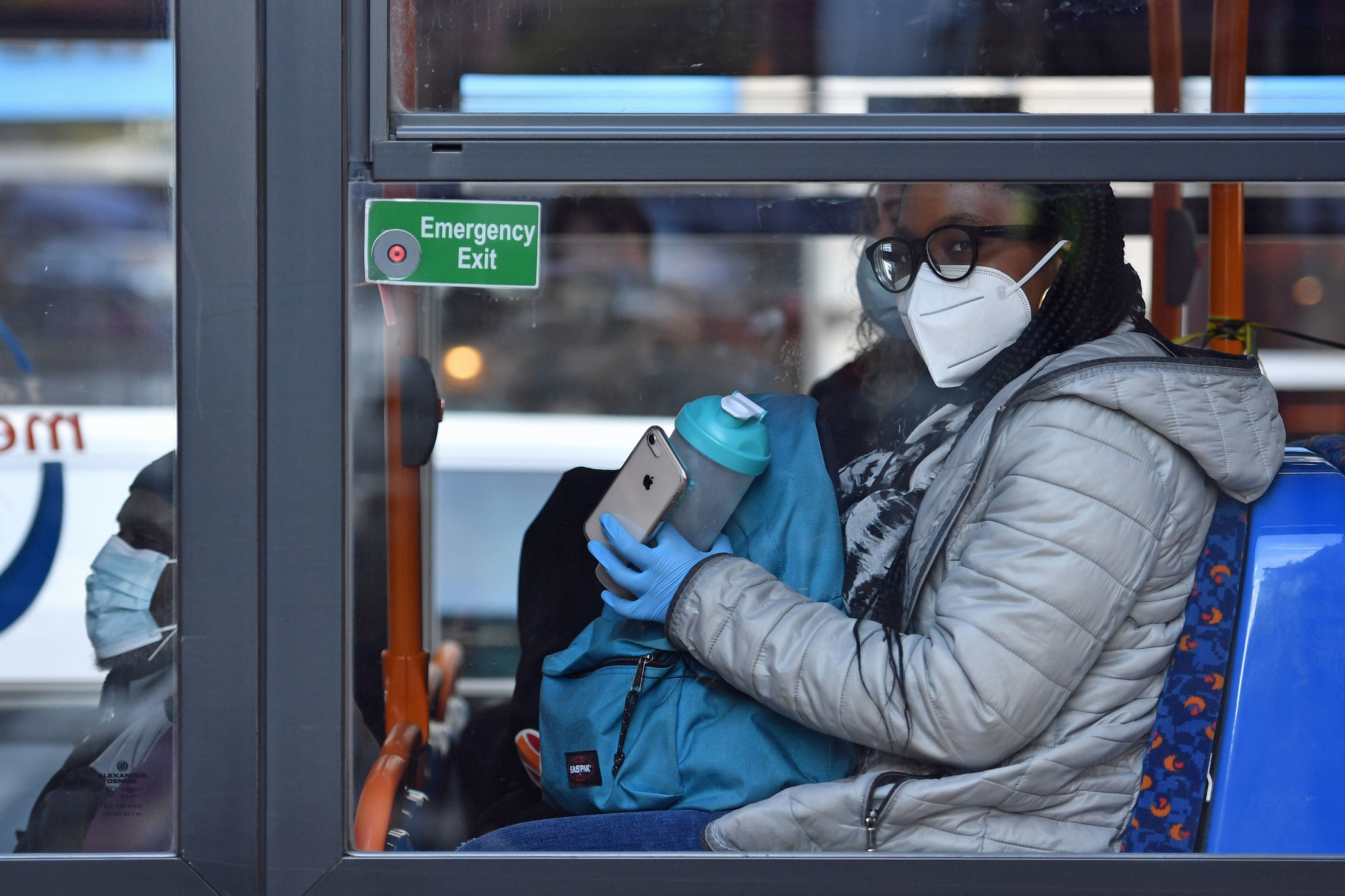 A person wearing a mask and gloves on a bus on Oxford Road in Manchester