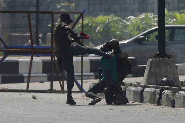 Un oficial de policía patea a un manifestante detenido por la puerta de peaje de Lekki en Lagos.