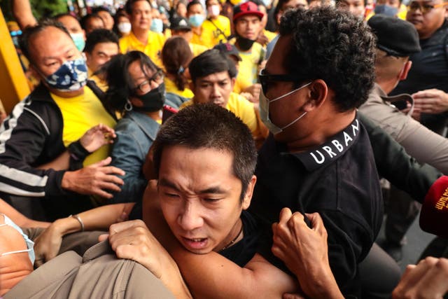 A man is held back during scuffles between royalist supporters and pro-democracy protesters at Ramkhamhaeng University in Bangkok on Wednesday