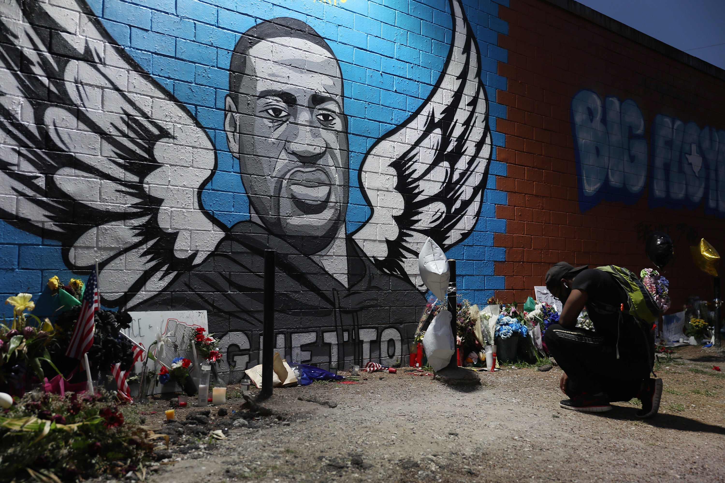 Joshua Broussard kneels in front of a memorial and mural that honors George Floyd at the Scott Food Mart corner store in Houston's Third Ward where Floyd grew up, on June 8, 2020 in Houston, Texas