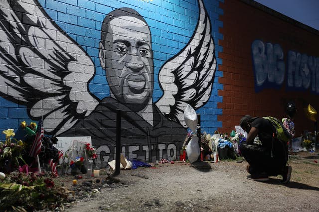 <p>Joshua Broussard kneels in front of a memorial and mural that honors George Floyd at the Scott Food Mart corner store in Houston's Third Ward where Floyd grew up, on June 8, 2020 in Houston, Texas</p>