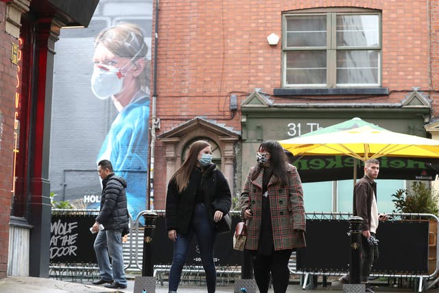 Las personas que llevan mascarilla caminan cerca de un mural de una enfermera en el Barrio Norte de Manchester.