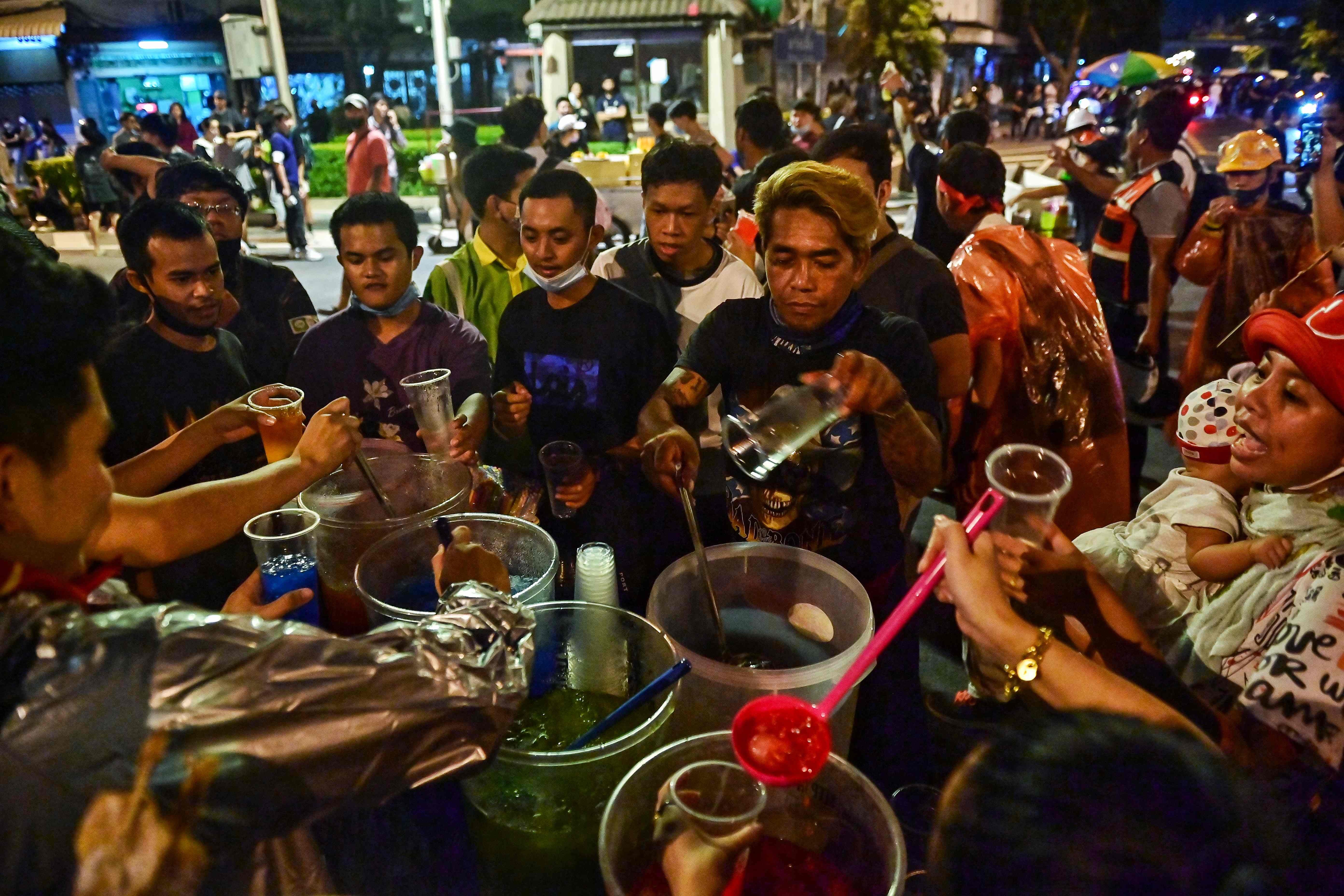 Pro-democracy protesters pause to grab drinks from a street vendor in Bangkok on Wednesday