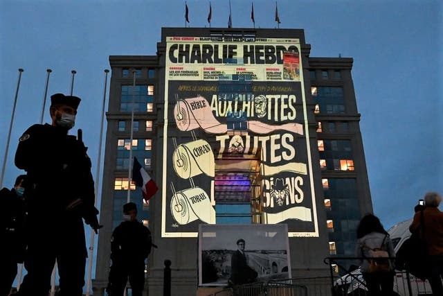 Police officers stand guard as cartoons of French satirical weekly newspaper Charlie Hebdo are projected onto the facade of the Hotel de Region in Montpellier, on 21 October, 2020
