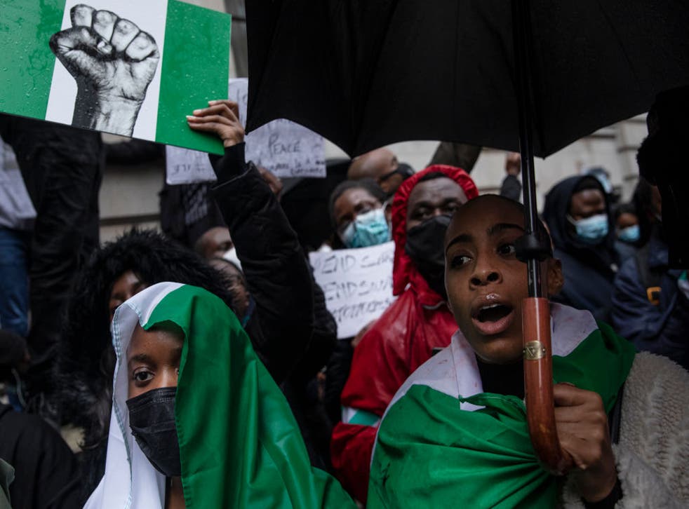 Protesters hold placards and signs calling for the end of police killings of the public in Nigeria, during a demonstration in London