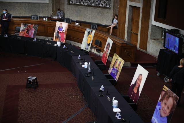 Images of people who’ve been helped by the Affordable Care Act occupy the seats of Democratic senators boycotting a Senate Judiciary Committee meeting on the nomination of Judge Amy Coney Barrett