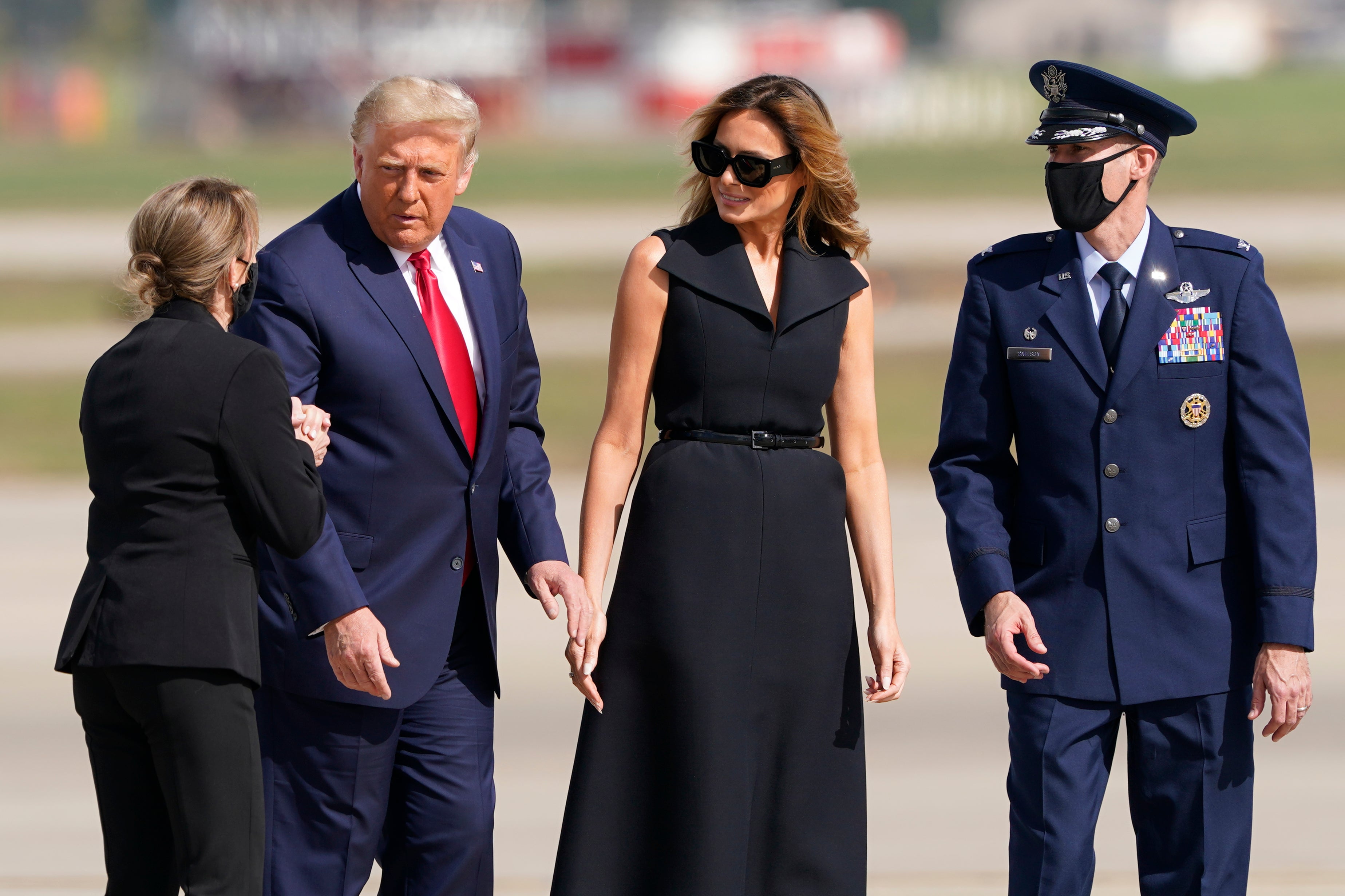 President Donald Trump and first lady Melania Trump talk with Catherine Nelson, left, wife of U.S. Air Force Col. Stephen Snelson, right, 89th Airlift Wing commander, right, as they walk from Marine One to Air Force One at Andrews Air Force Base