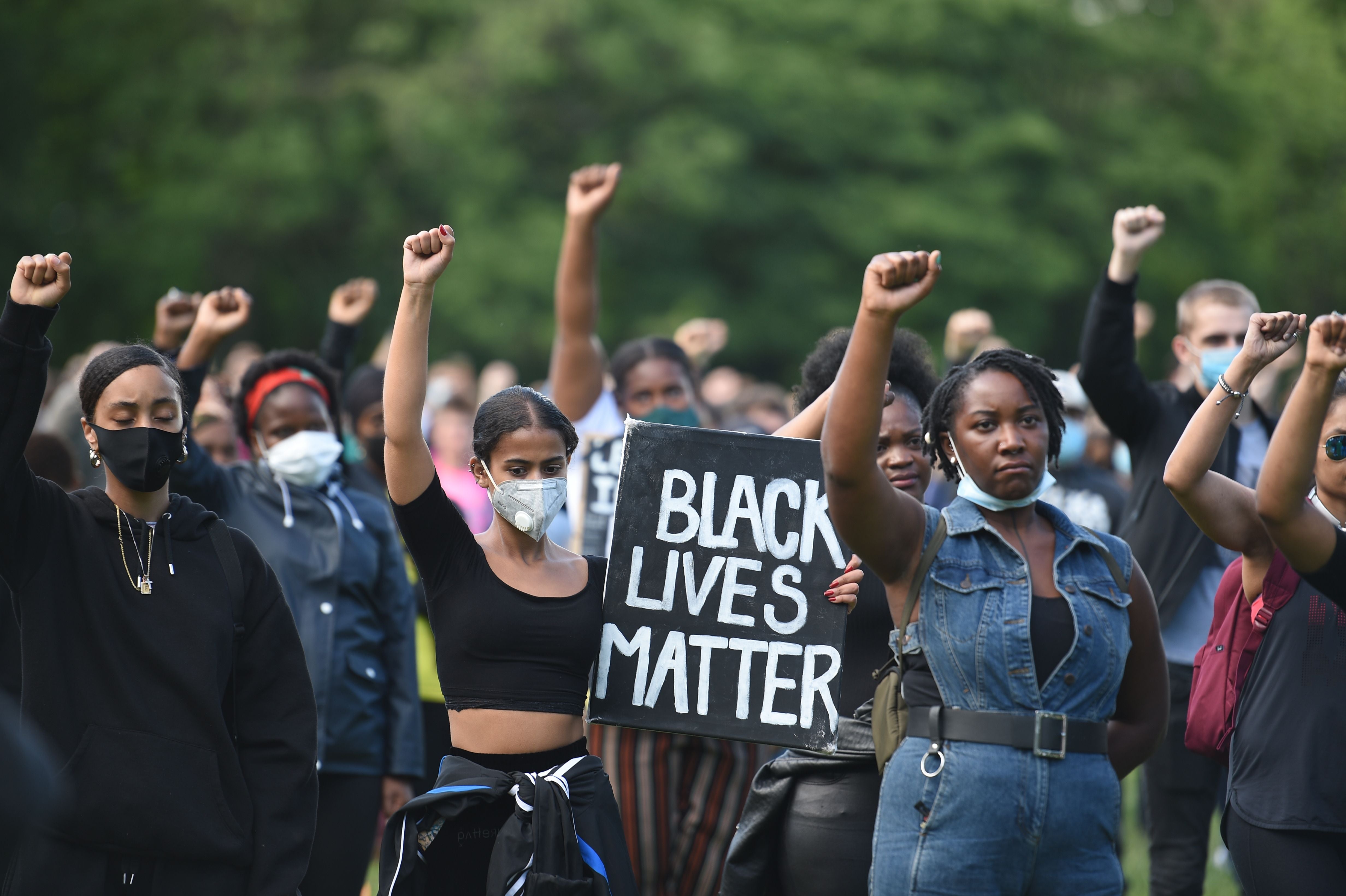 TOPSHOT - Protesters hold up fists at a gathering in support of the Black Lives Matter movement on Woodhouse Moor in Leeds in northern England on June 21, 2020, in the aftermath of the death of unarmed black man George Floyd in police custody in the US.