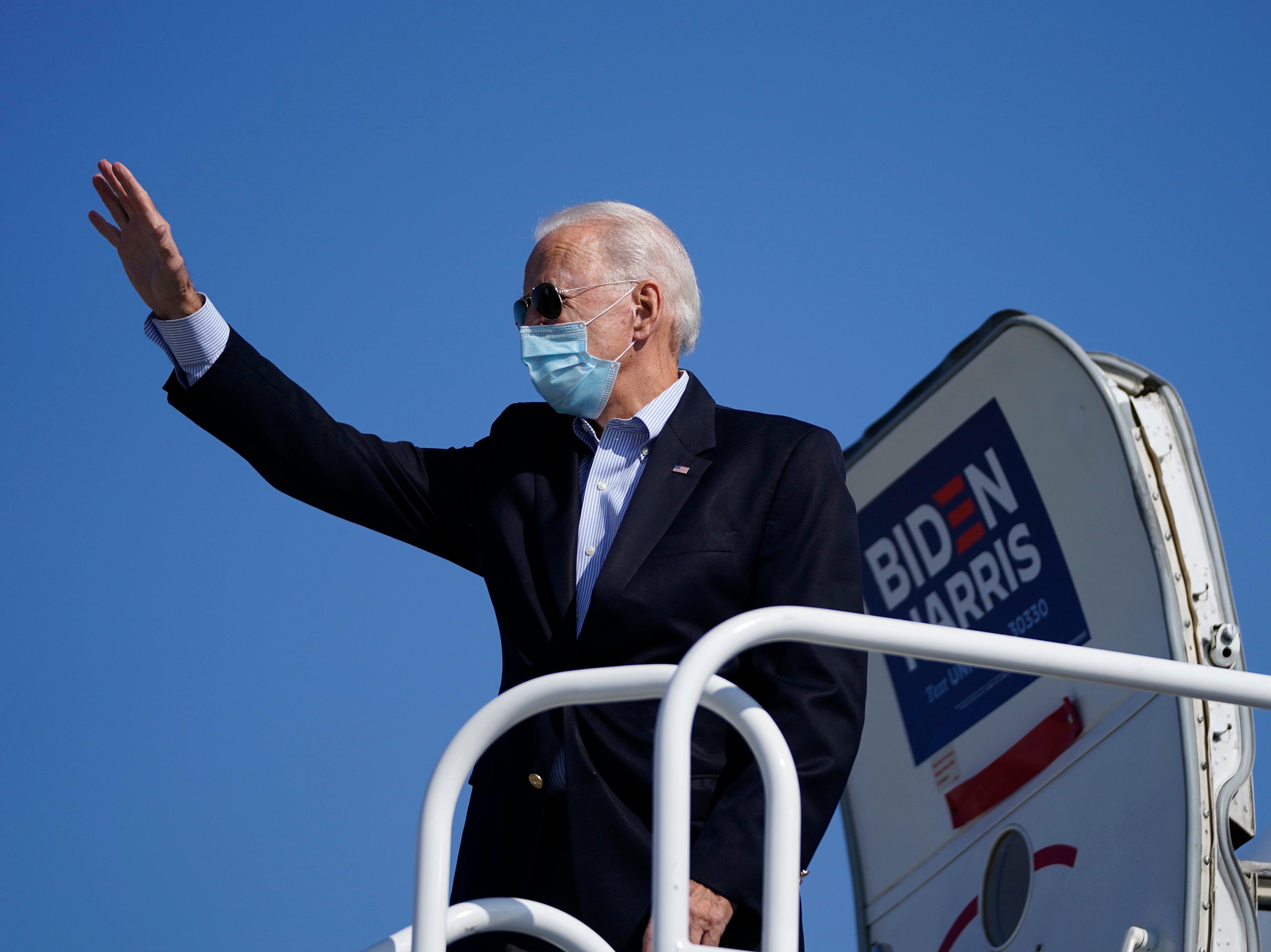Democratic presidential nominee Joe Biden waves before boarding his campaign plane at New Castle Airport on 22 October 2020