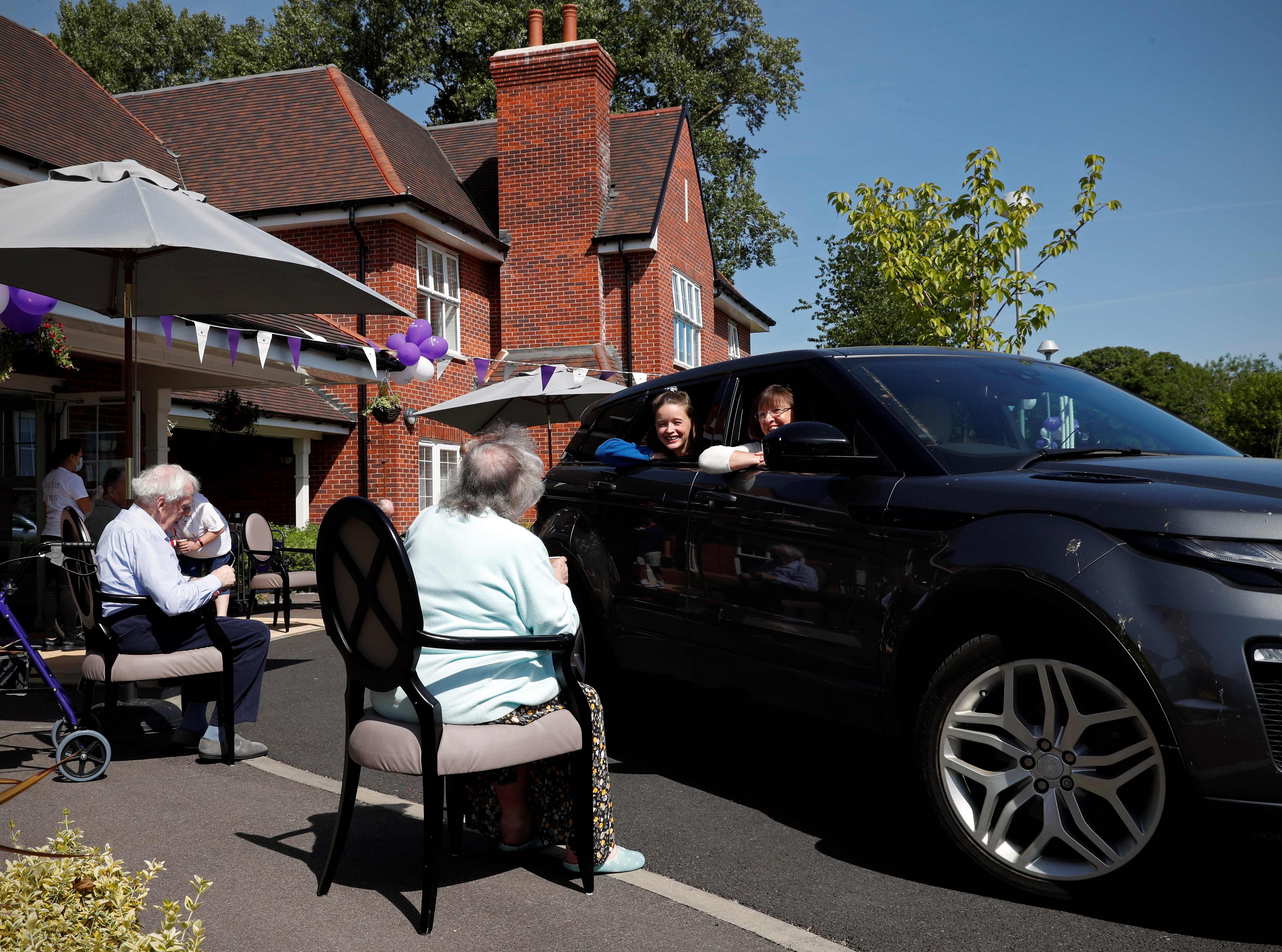 Elderly care home residents socially distance from visitors