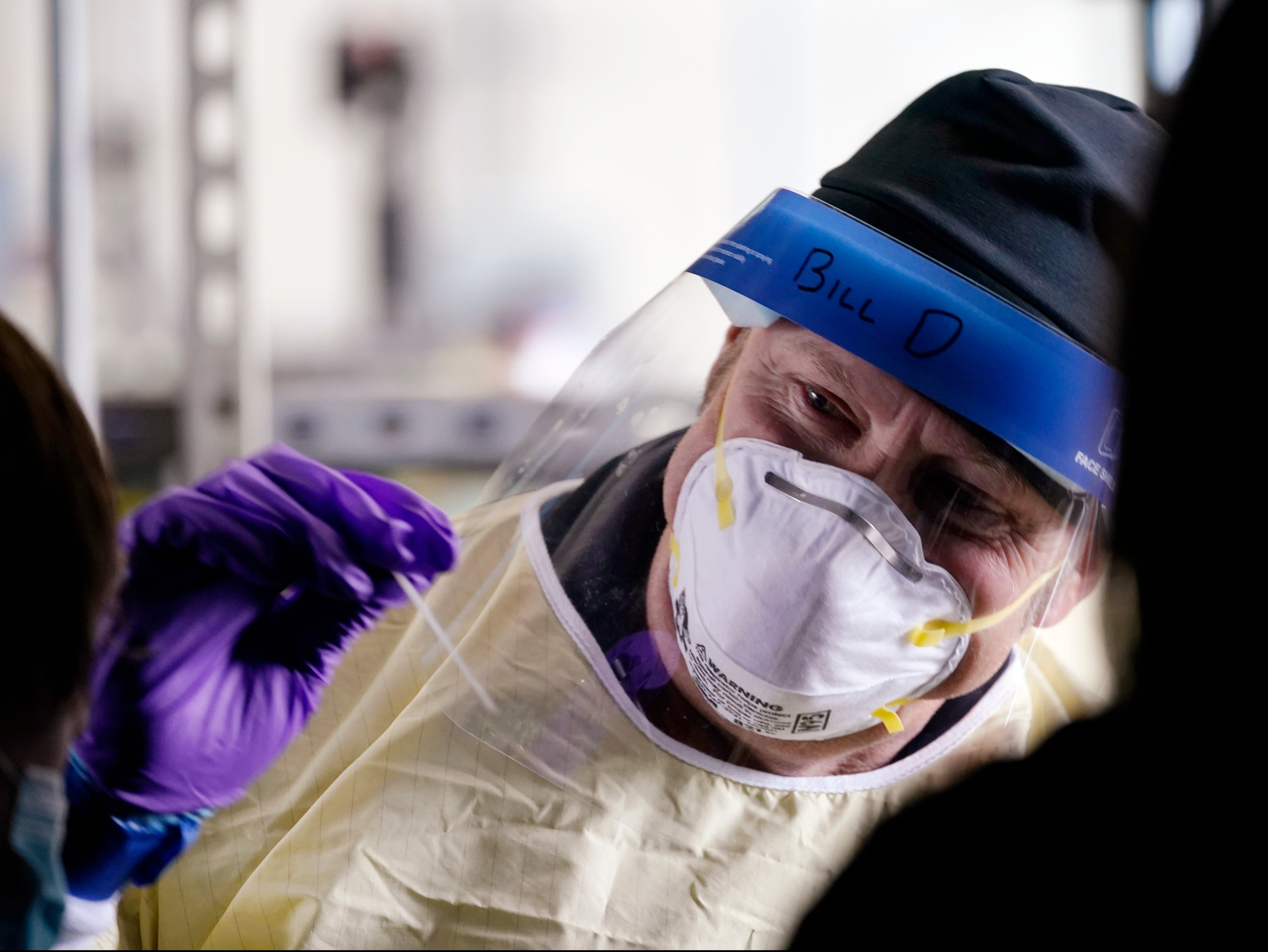 Seattle firefighter Bill Dennis reaches in to take a sample from a passenger in a car at a free Covid testing site Friday, 23 October, 2020, in Seattle